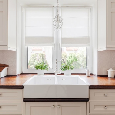 Kitchen sink under window with roman blinds half drawn.