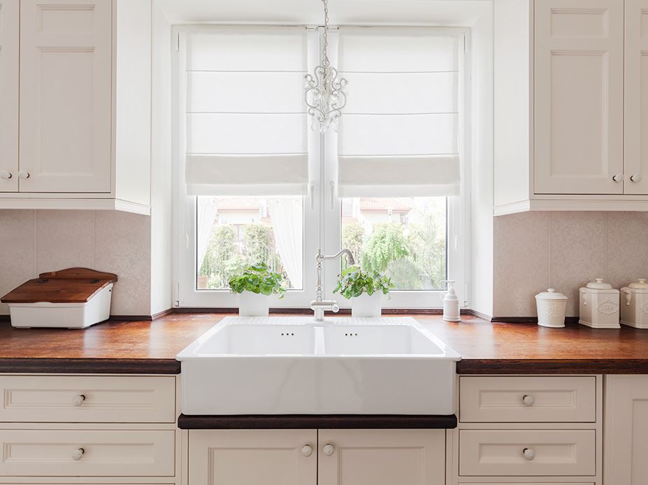 Kitchen sink under window with roman blinds half drawn.